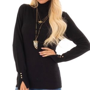 Black turtleneck top with gold cuff links